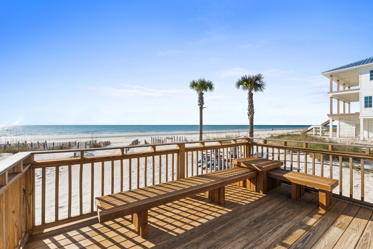 Beachfront deck offers direct ocean views with palm trees and sandy shores just steps away from your private retreat.