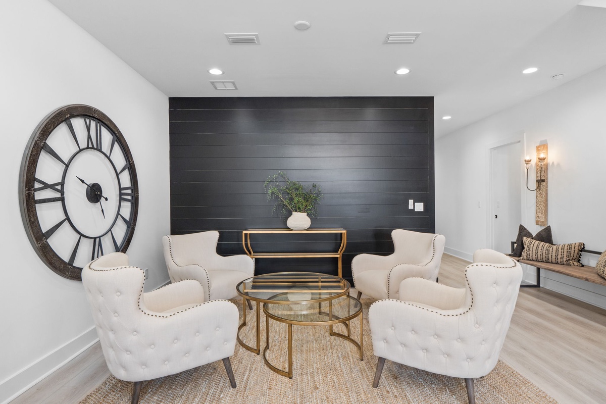 Relax in this elegant seating area with plush tufted chairs and striking dark wood accent wall that creates the perfect atmosphere for conversation.