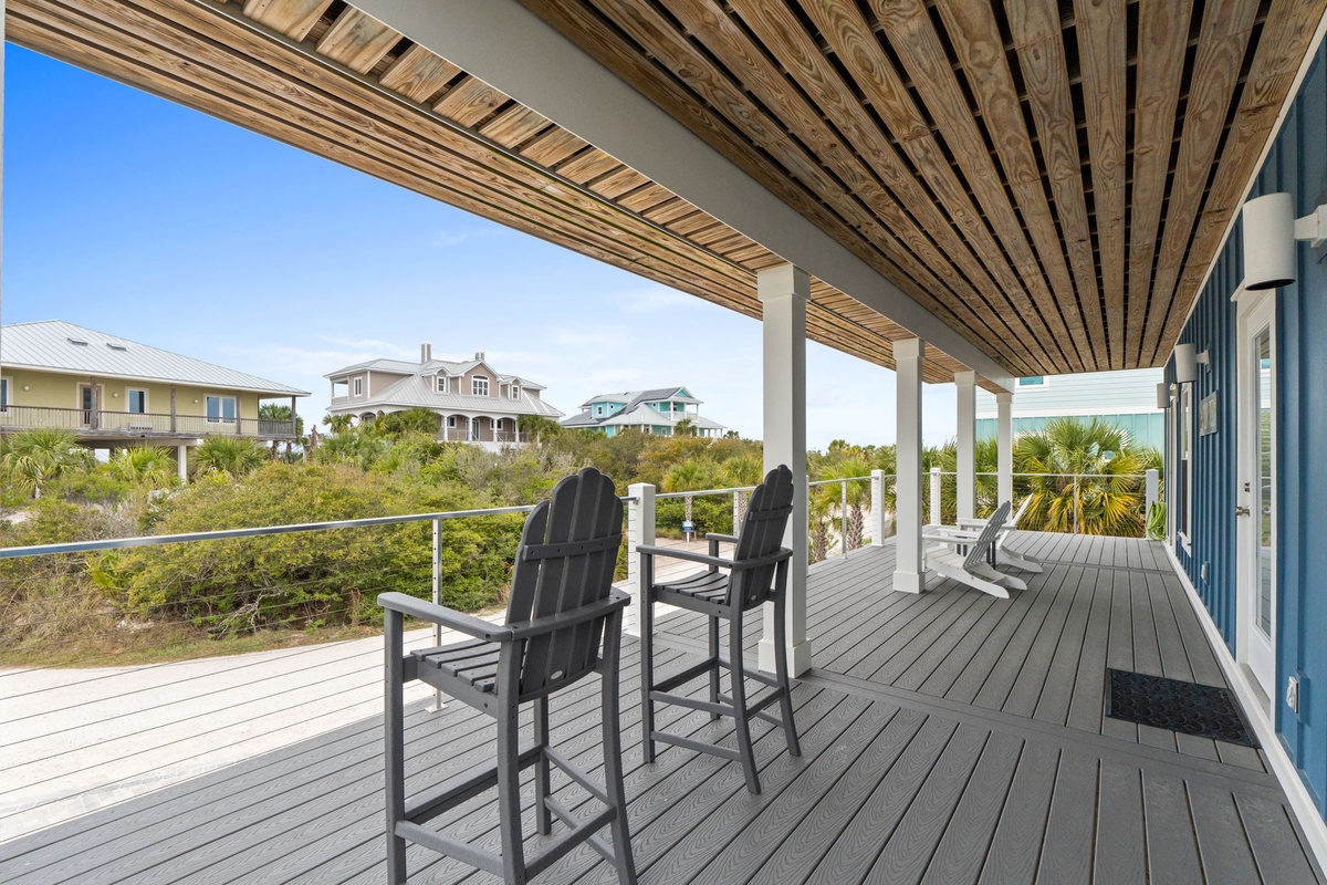 Relax on your private deck with coastal views, where modern comfort meets seaside charm under the warm wooden pergola.