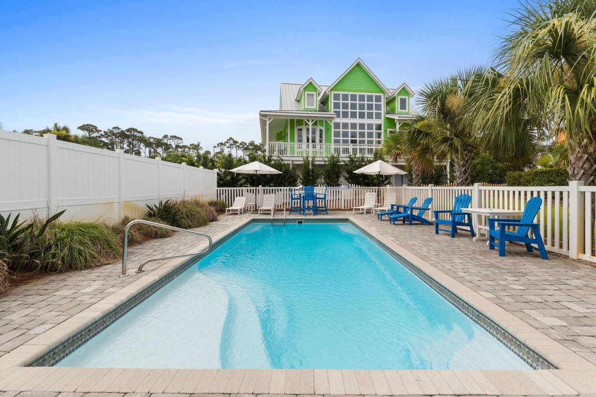Bright coastal retreat with private pool surrounded by lounge chairs and palms, perfect for sun-soaked relaxation in a beachside setting.