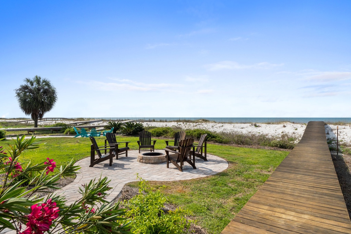 The property features a beachfront fire pit and seating area with direct boardwalk access to sandy shores and Gulf views.