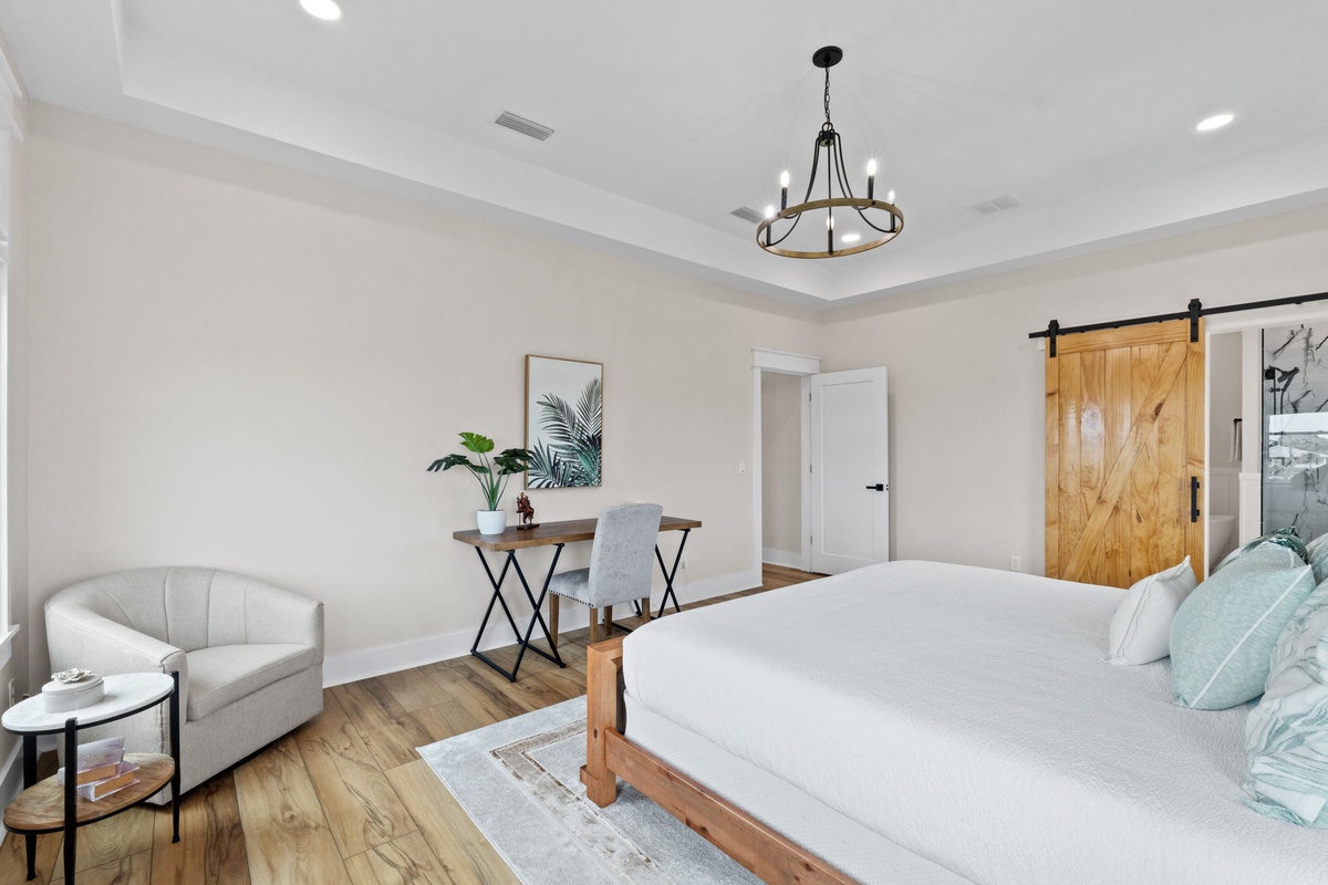 Unwind in this airy bedroom with crisp linens, warm wood accents, and a cozy loveseat perfect for curling up with a book after a day of exploring.