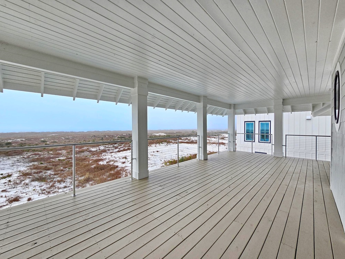 Spacious covered deck overlooking pristine coastal landscape with white sand dunes and native vegetation stretching to the horizon.