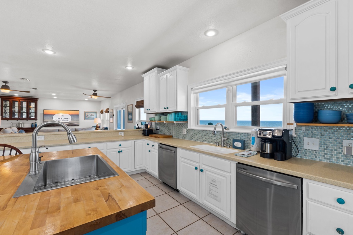 Bright coastal kitchen with ocean views, natural wood counters, and crisp white cabinetry accented with playful turquoise touches—your perfect beachside retreat for cooking and entertaining.