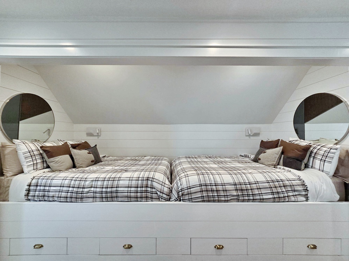 Drift off to sleep in your cozy nook featuring queen beds with soft plaid bedding and handy built-in storage drawers beneath.