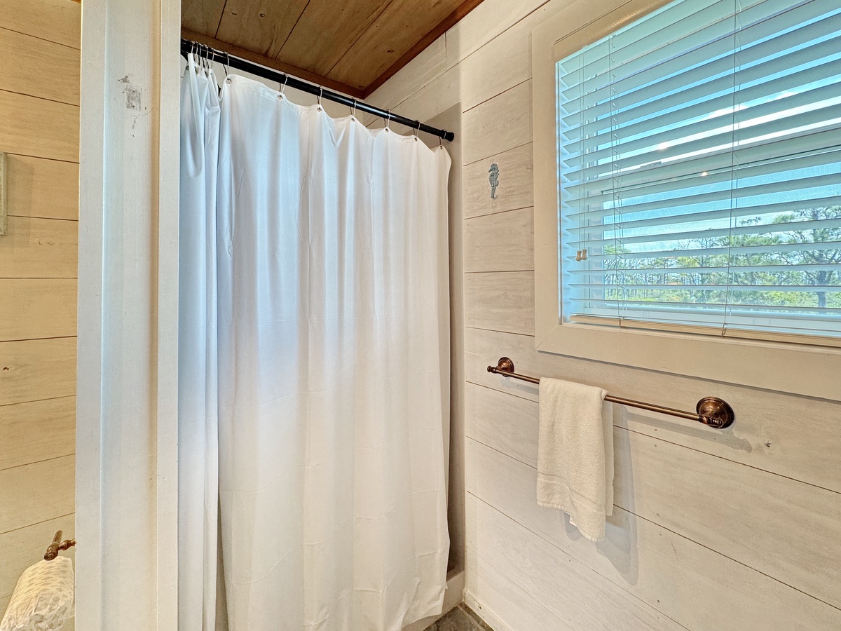 Step into your rustic bathroom with exposed wood beams, crisp white linens, and natural light filtering through the blinds for a peaceful morning routine.