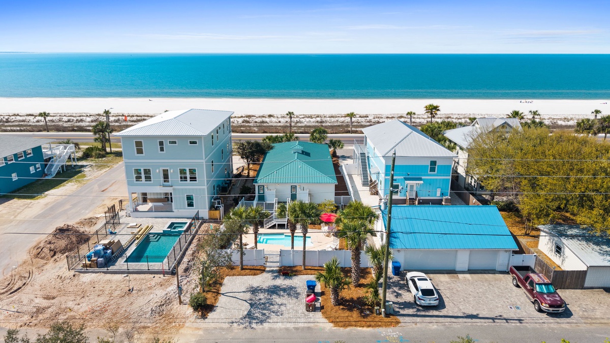 Aerial view of beachfront vacation rental properties with swimming pools, just steps from pristine white sand beaches and turquoise waters.