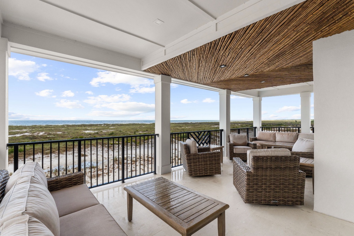 Spacious covered terrace offering panoramic views of coastal wetlands and the distant ocean horizon under a natural wood-beamed ceiling.
