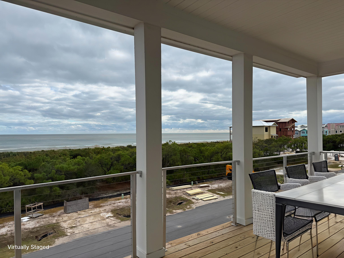 Covered deck offering sweeping ocean views and coastal home scenery beyond the green landscape.