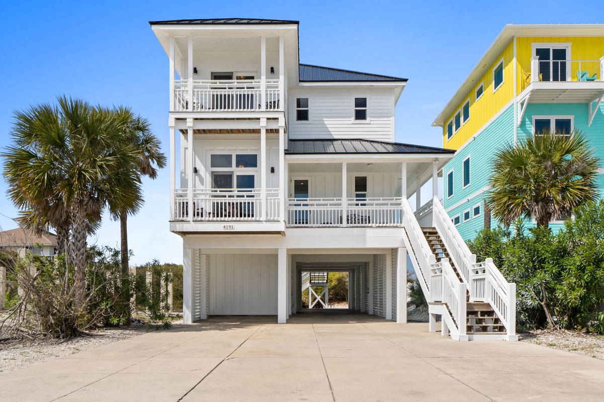 Stunning three-story beach house with elevated design, multiple balconies, and tropical palm surroundings in a vibrant coastal neighborhood.