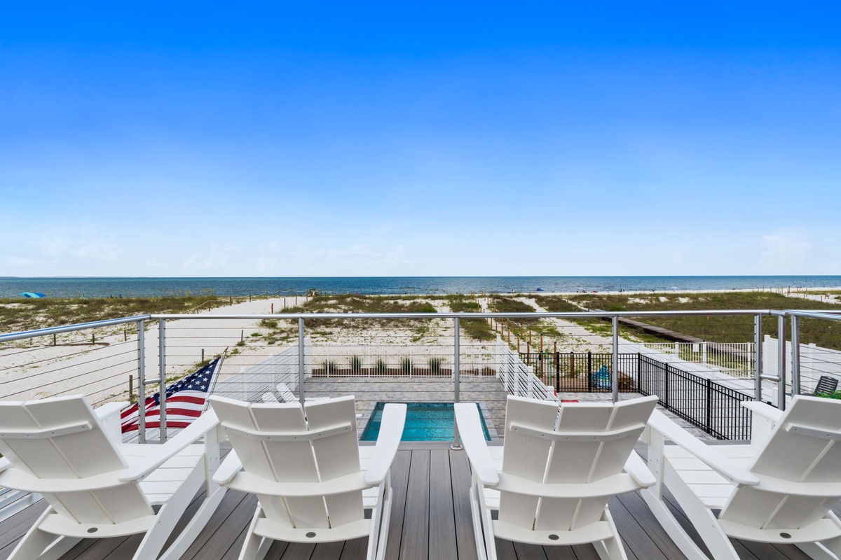 This beachside deck showcases a pristine pool, sun loungers, and unobstructed ocean views. The property sits directly on sandy shores beneath clear blue skies—ideal for sun-soaked days.