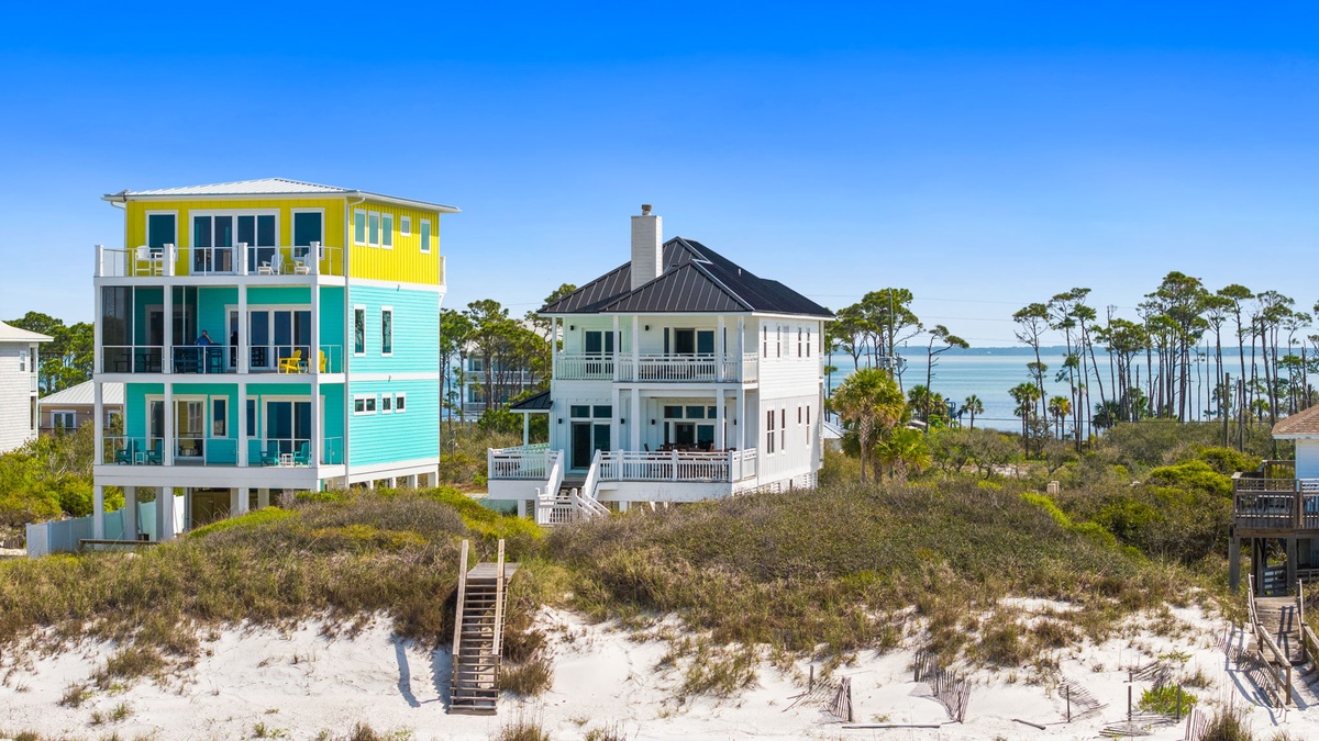 Colorful beachfront homes with natural dune vegetation and pristine white sand create a stunning coastal setting.