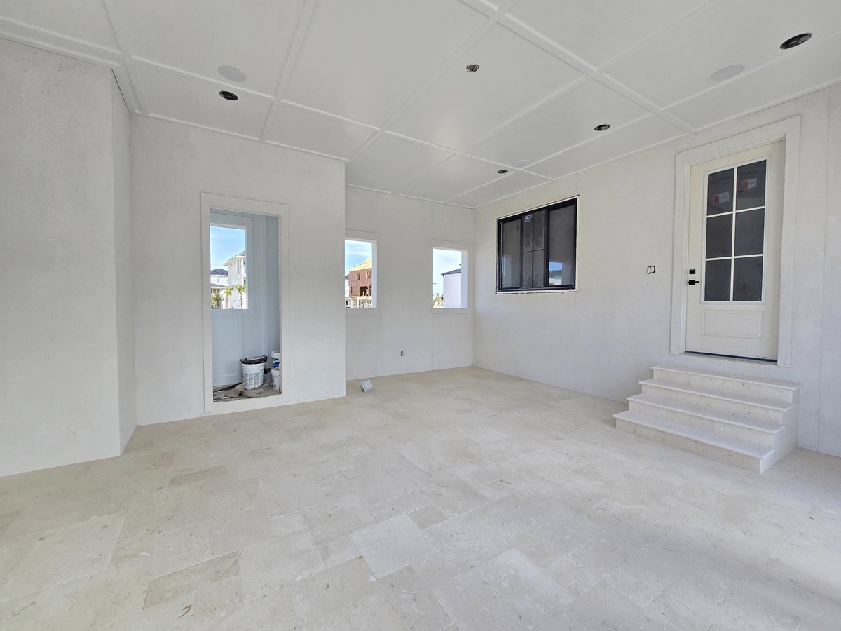 Step into your bright, spacious living area with soaring coffered ceilings and abundant natural light streaming through multiple windows.