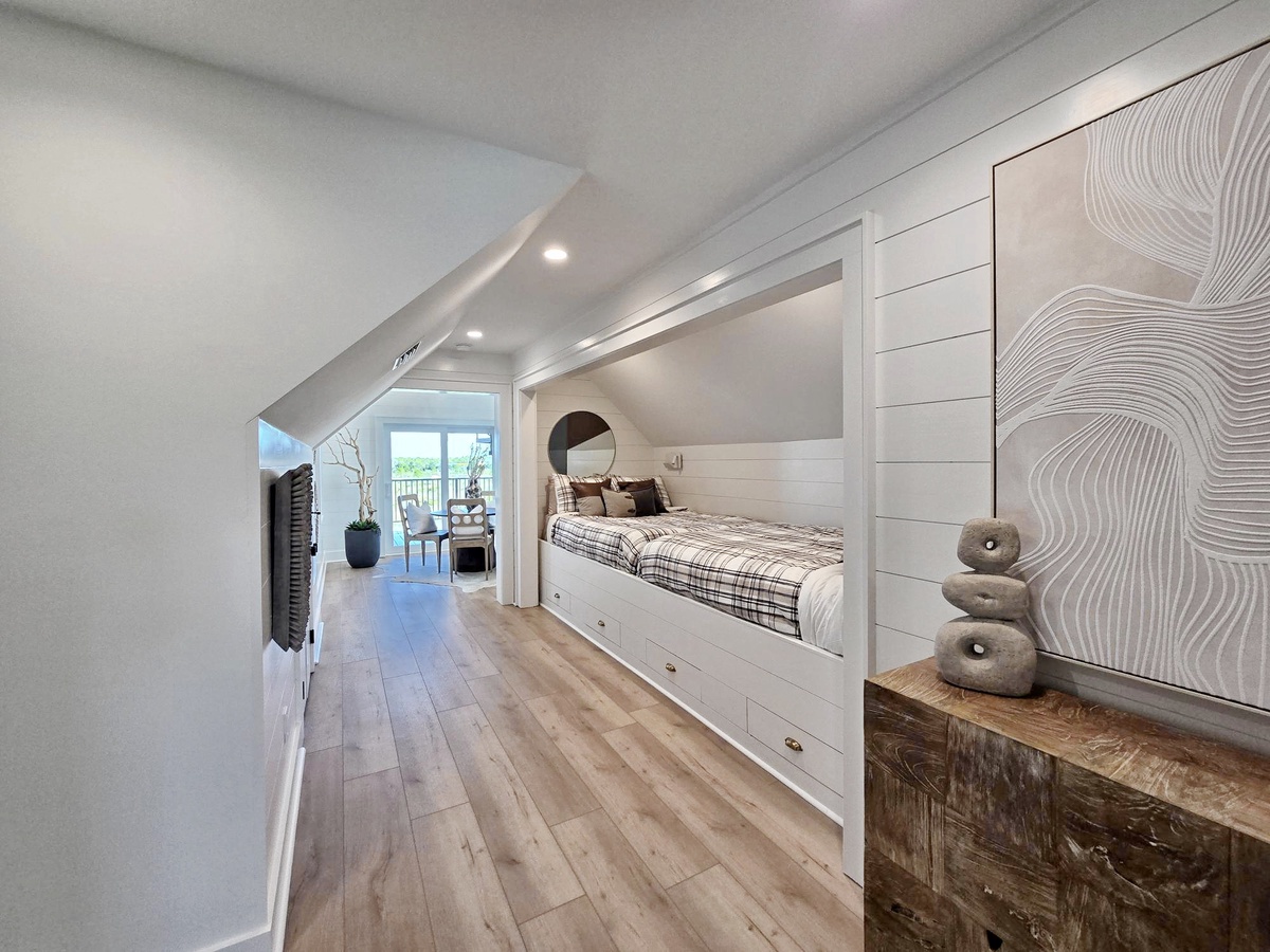 Slip into your cozy built-in bed nook with custom storage drawers beneath, where warm wood floors and thoughtful lighting create the perfect retreat.