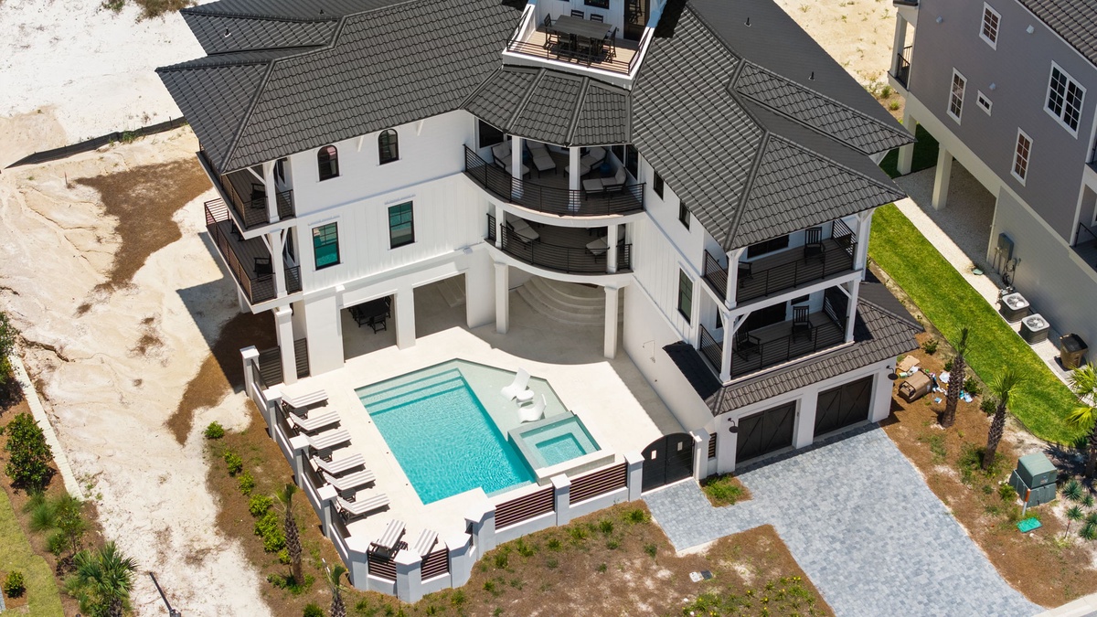 Aerial view capturing a modern coastal vacation home featuring a private pool, spacious balconies, and convenient beach access in a serene residential neighborhood.