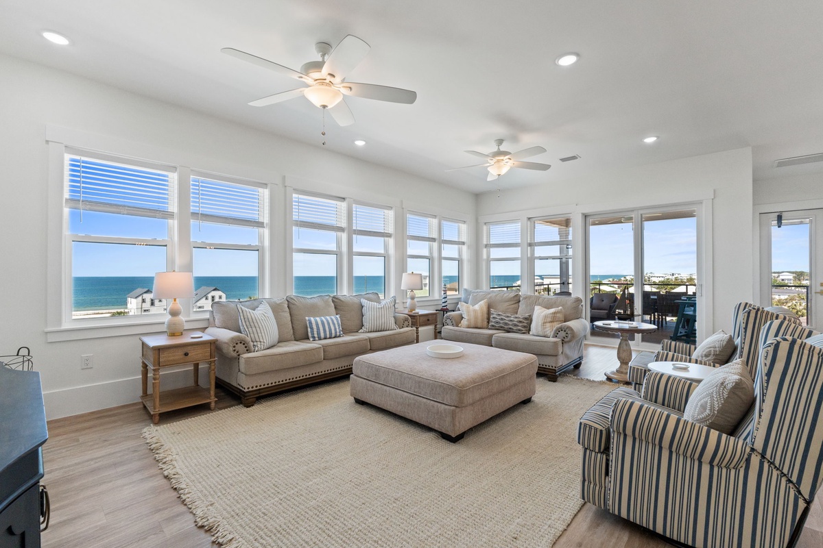 Relax in your bright living room with stunning ocean views through floor-to-ceiling windows and comfortable seating.