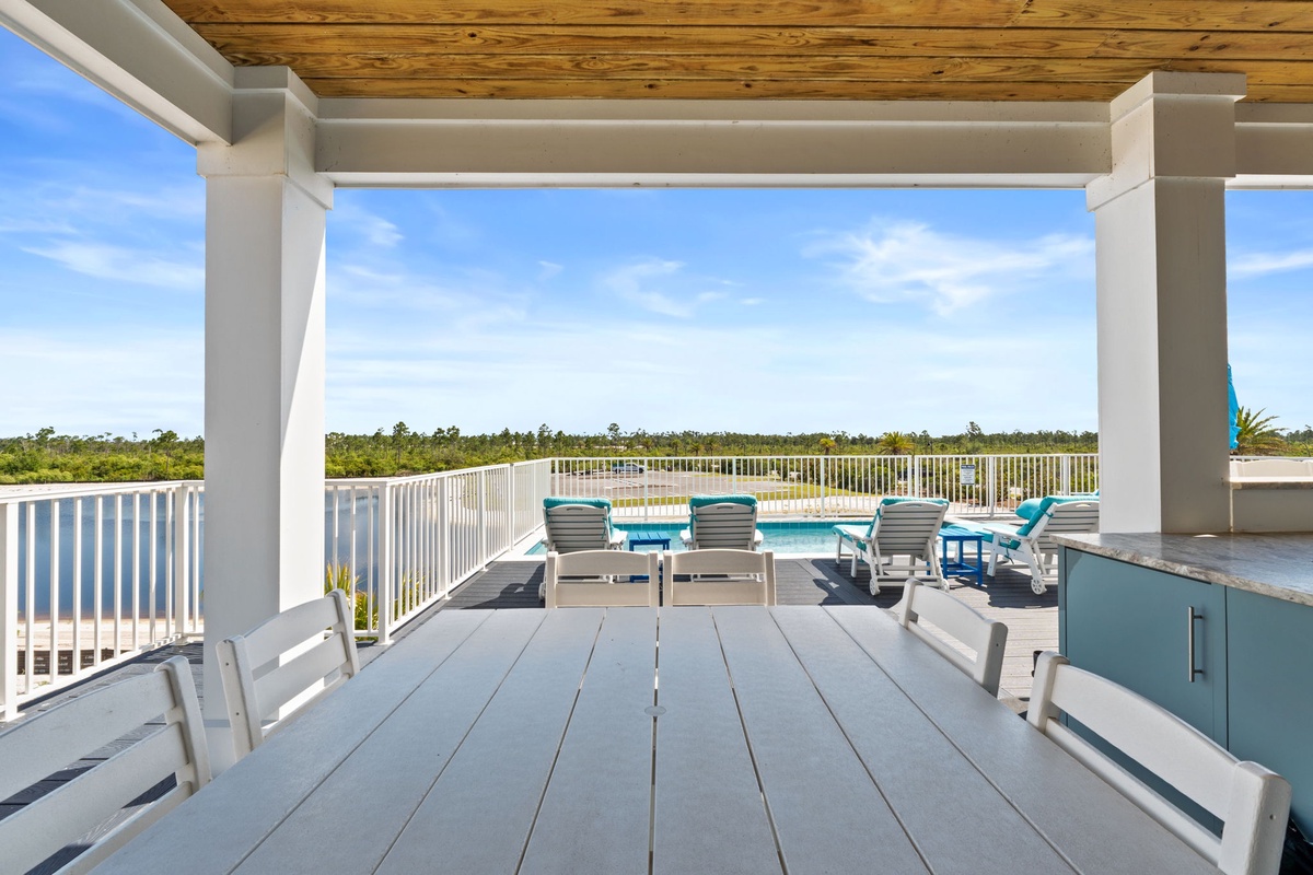 A rooftop terrace overlooking natural wetlands provides an outdoor entertainment space with covered seating, dining areas, and scenic views of the surrounding landscape.