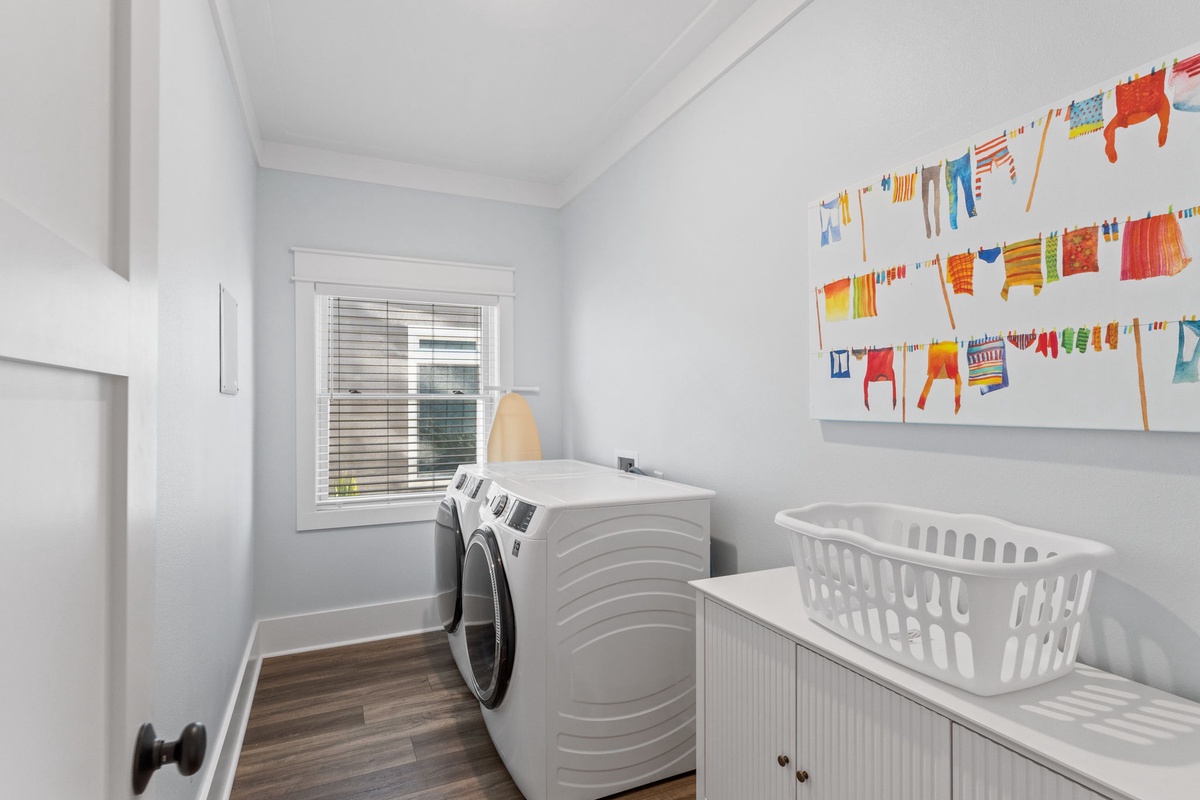 Fresh, dedicated laundry space with front-loading machines and cheerful artwork—keeping your vacation wardrobe ready for every adventure.