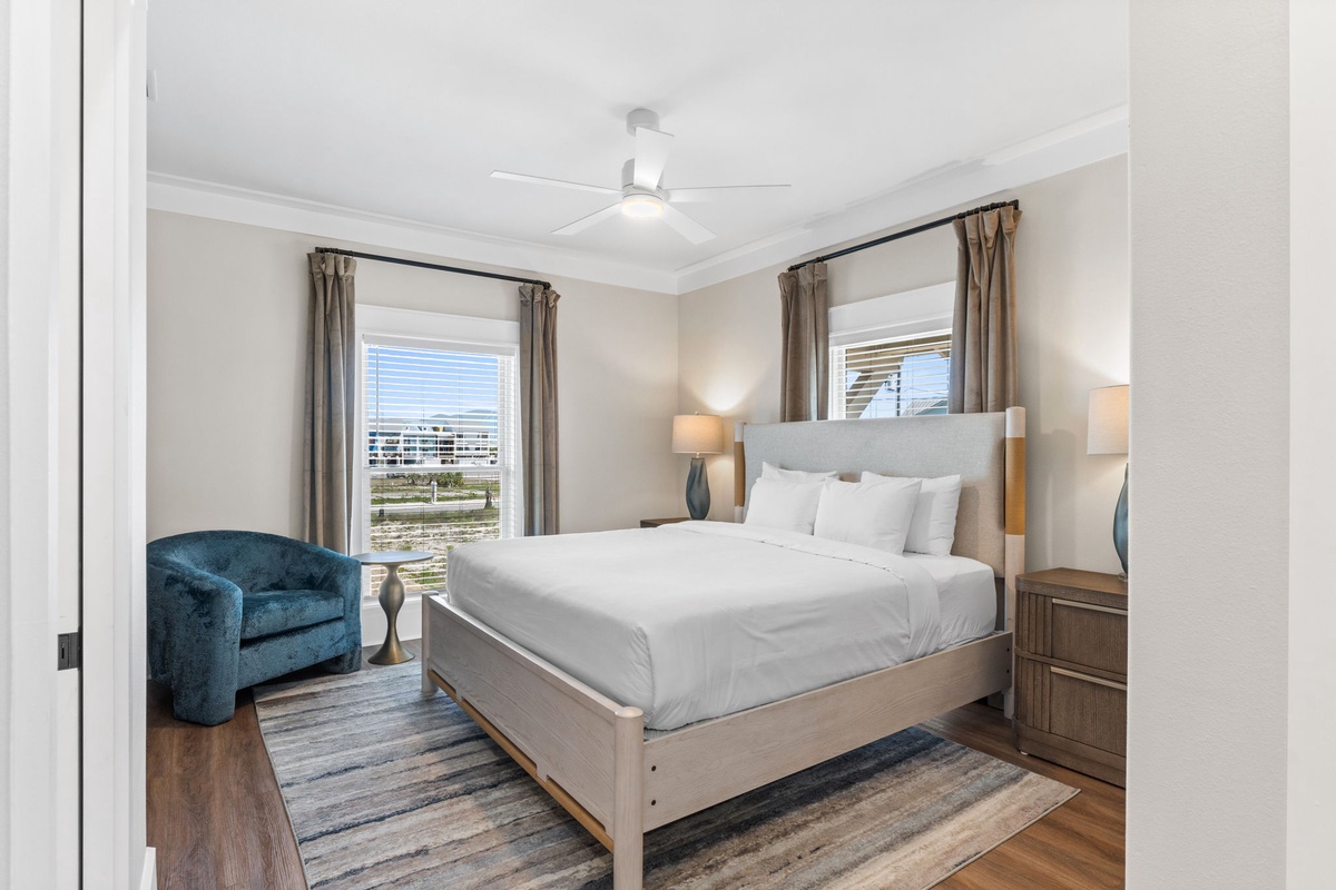 Unwind in your peaceful bedroom with plush bedding, a cozy reading chair, and natural light framing views of the surrounding area—a serene retreat after each day.