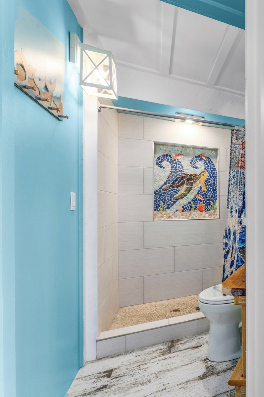 Step into your bright coastal poolside bathroom featuring a stunning sea turtle mosaic and cheerful blue accents.