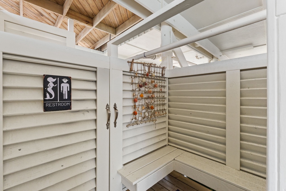 A charming outdoor restroom with coastal character—open beams overhead, rustic nautical details, and whitewashed wood give this space a relaxed, beachy vibe.