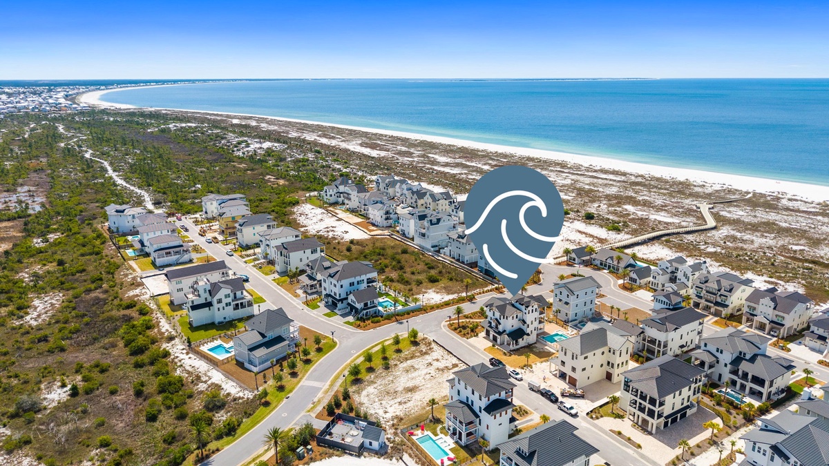 Aerial view of a coastal residential development featuring modern homes and pristine beachfront just steps away from the shoreline.