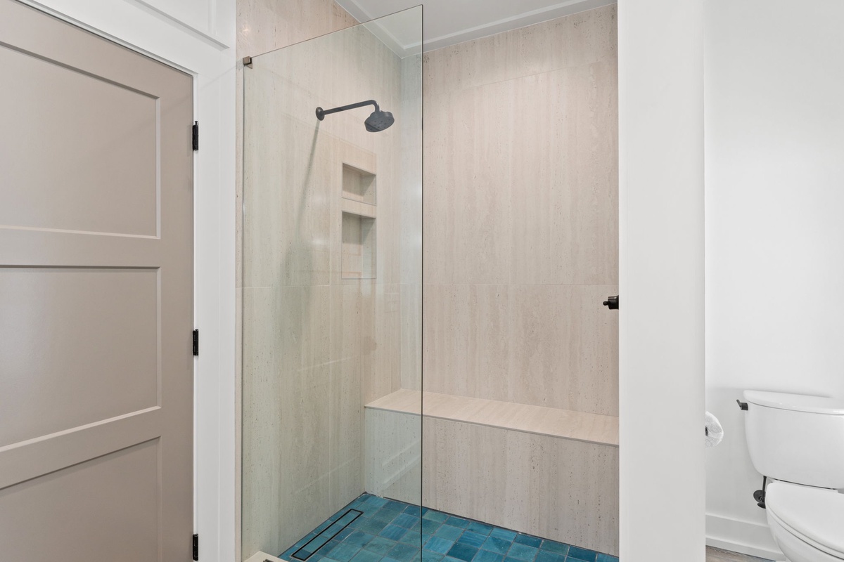 Step into your modern bathroom sanctuary with sleek glass shower, rainfall head, and built-in bench for ultimate relaxation.