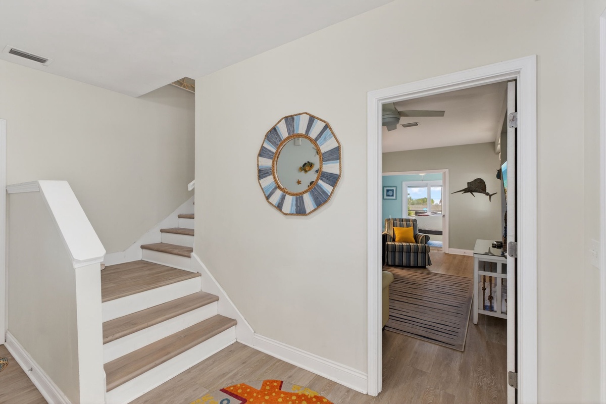 Your coastal-inspired hallway connects spaces with warm wood floors and charming nautical touches, leading to comfortable living areas.