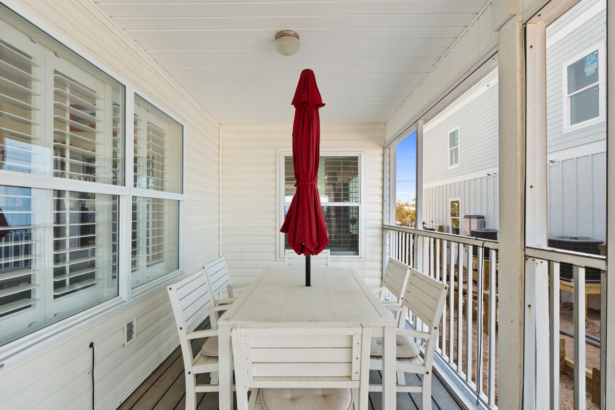 Your covered balcony offers fresh air dining with a spacious table for six and peaceful neighborhood views.