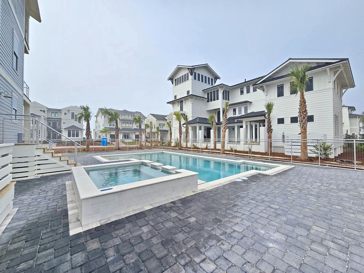 Beautiful pool and hot tub await your relaxation, surrounded by coastal architecture and palm trees in this serene community setting.