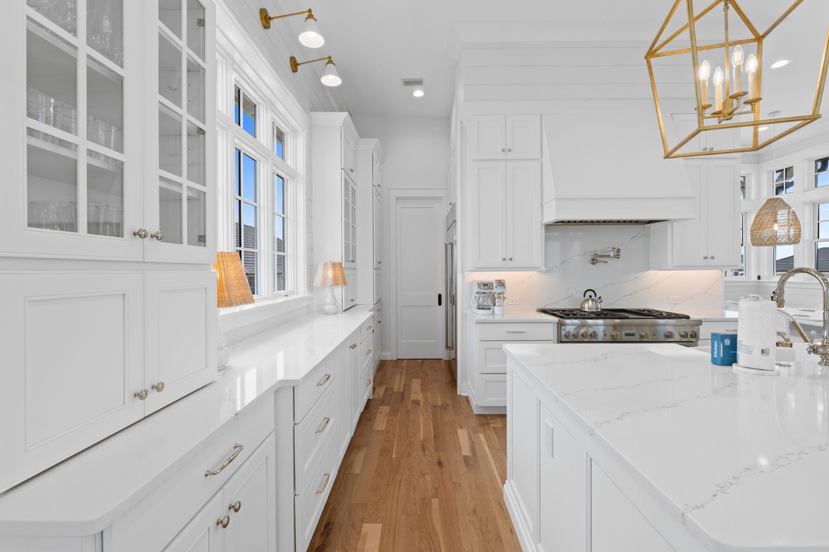 Picture yourself preparing meals in this bright, elegant kitchen with gleaming white cabinetry, marble countertops, and top-of-the-line appliances—your culinary retreat awaits.