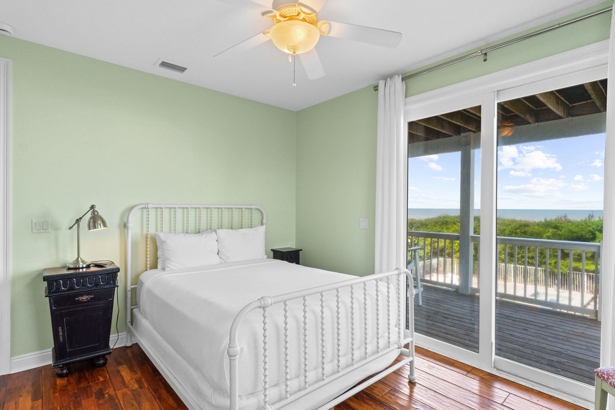 Wake up to your own private sea view each morning from this tranquil bedroom, where soft green walls and an elegant white bed invite you to relax and recharge.