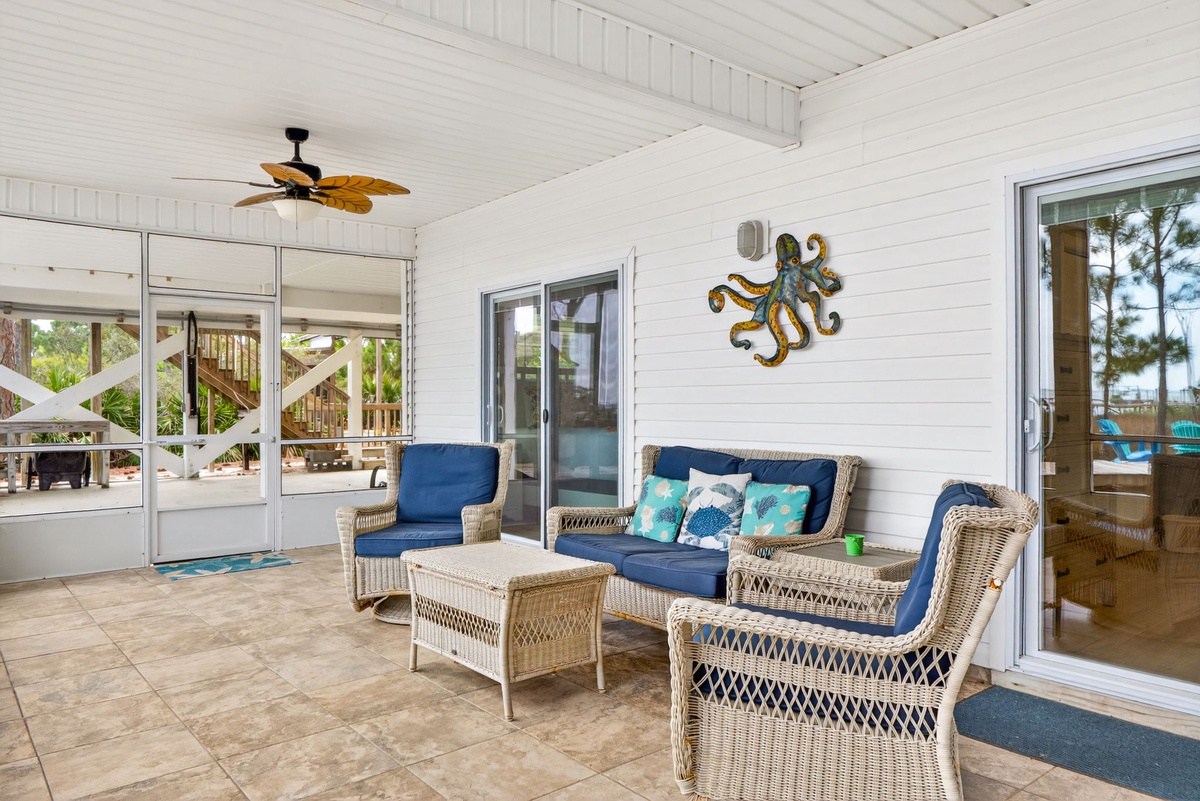 Your private screened porch invites you to unwind with comfortable wicker seating and coastal charm.