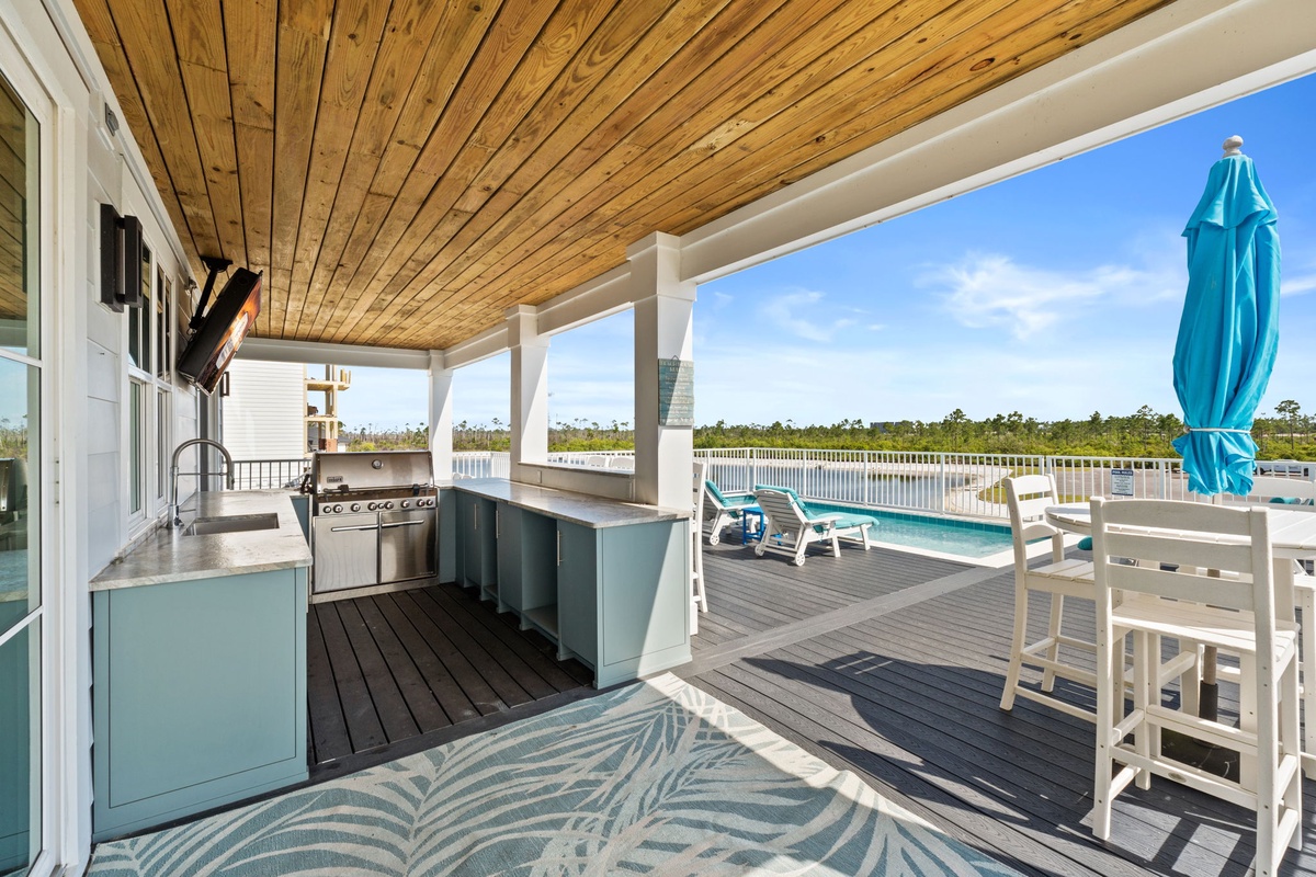 Your covered deck features a full outdoor kitchen with stainless appliances, a dining table for eight, and stunning waterfront views—ideal for grilling sunset dinners while you relax by the pool.