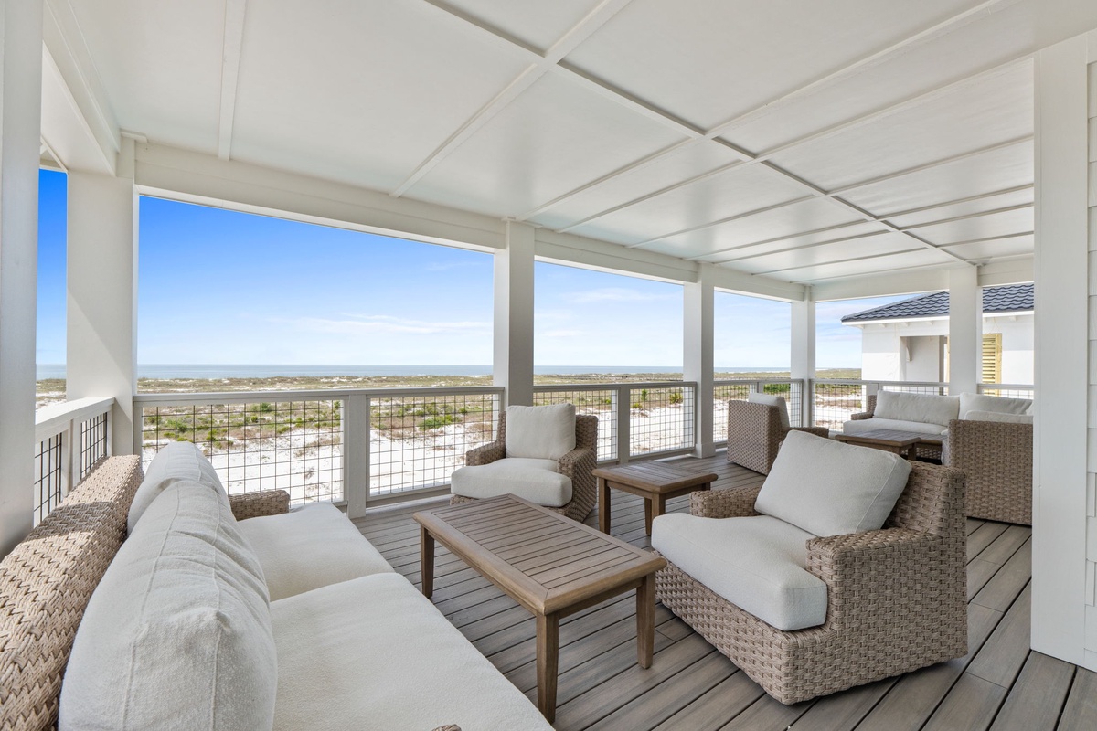 Sink into plush wicker seating on your covered terrace and soak in sweeping views of the coastal landscape and shimmering waters. This breezy retreat invites you to unwind in total comfort.