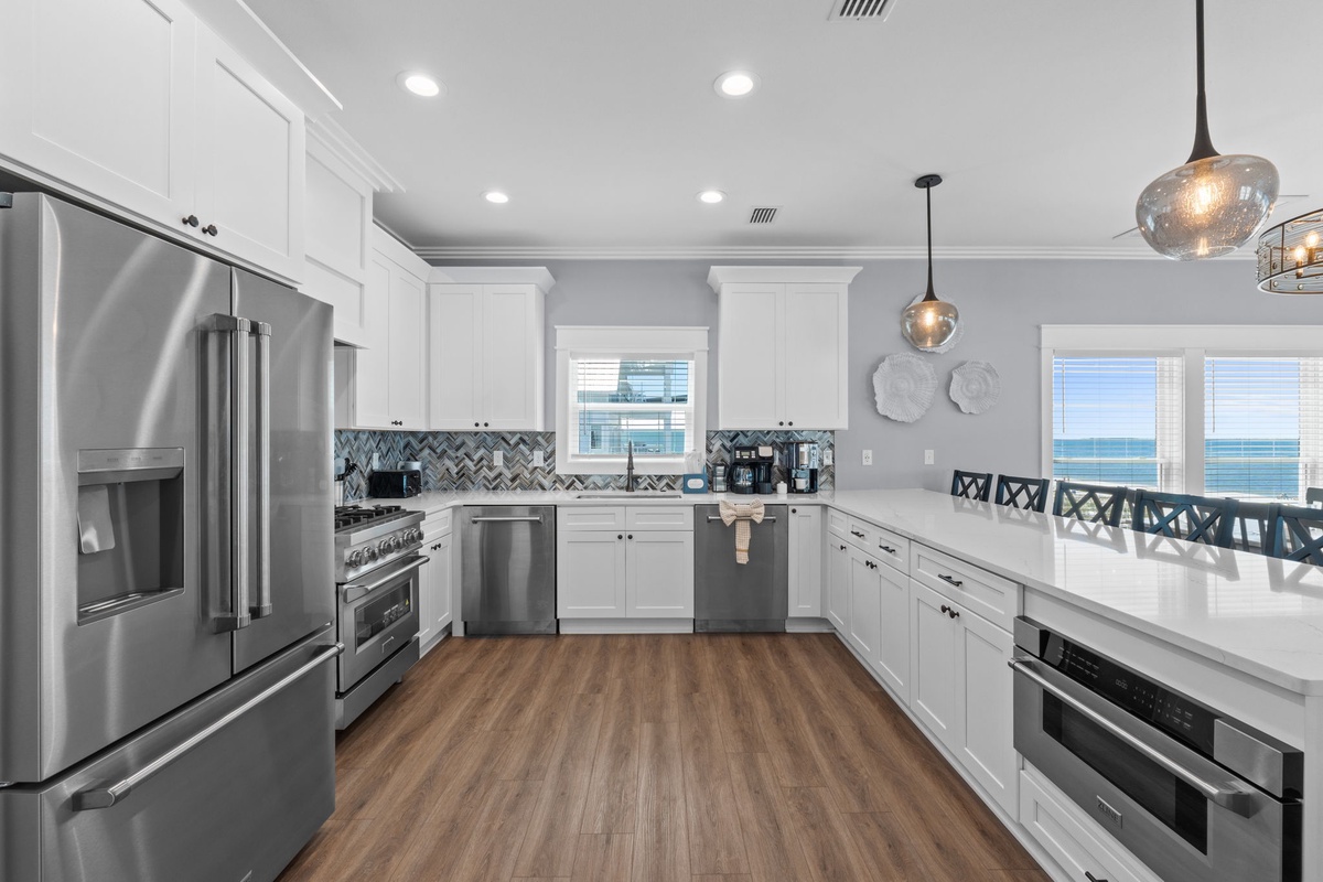 Your gourmet kitchen awaits with sleek stainless steel appliances, custom cabinetry, and stunning ocean views through large windows—perfect for preparing meals while soaking in the coastal scenery.