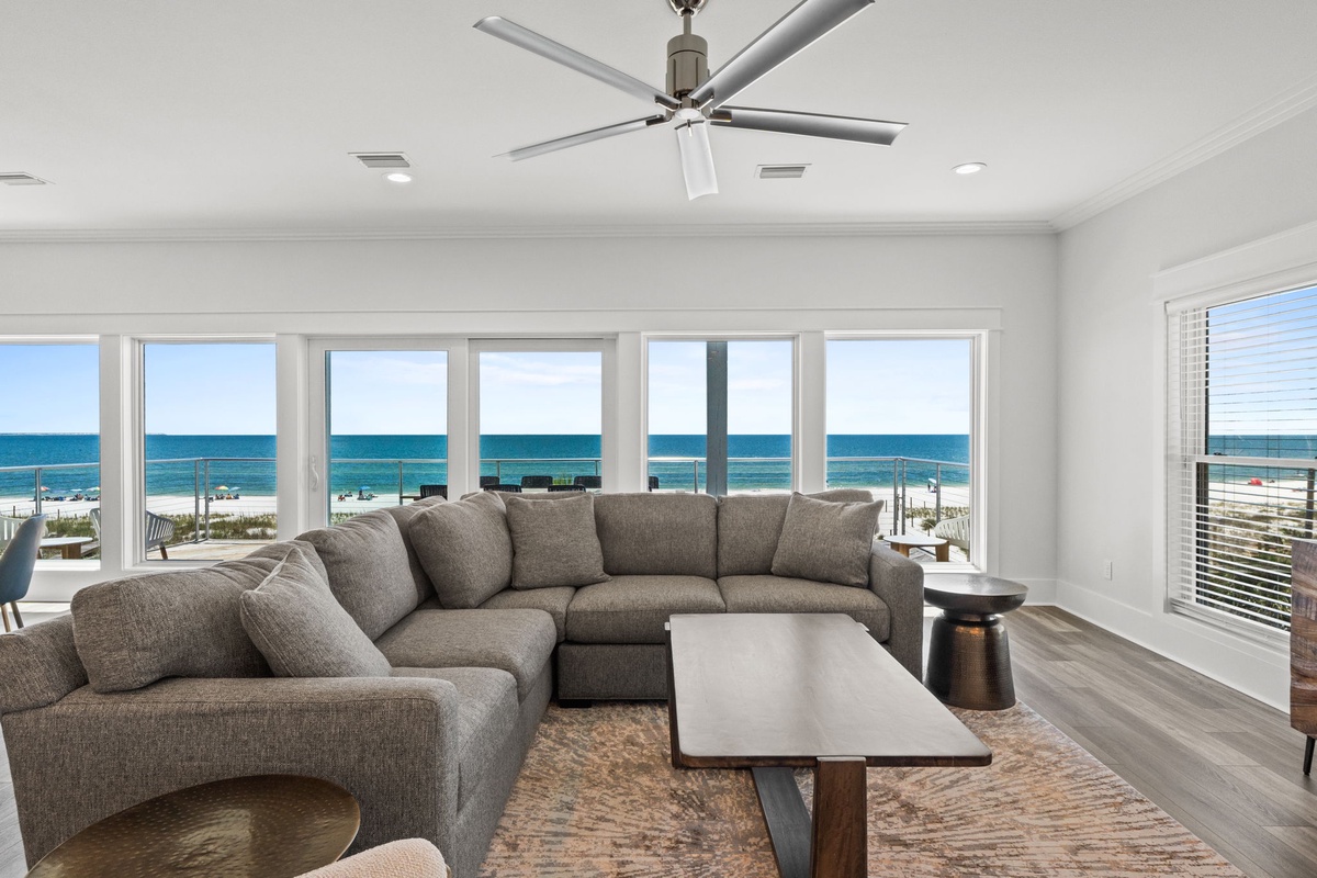 Relax in your spacious living room as expansive windows frame breathtaking ocean views. Modern comfort meets coastal elegance with plush seating and direct beach access steps away.