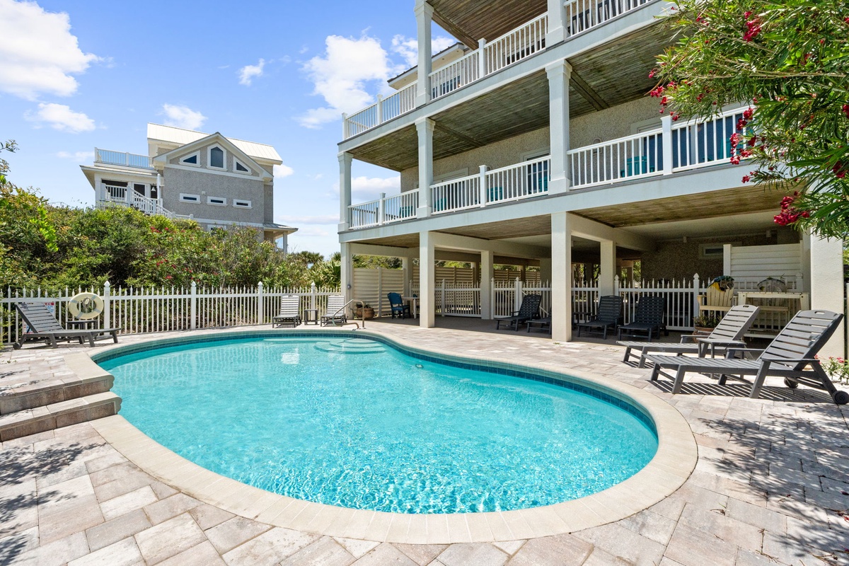 Three-story coastal retreat features private pool surrounded by spacious decking, shaded covered areas, and lounge seating—your perfect spot to soak up the sunshine.