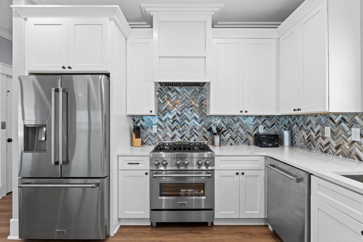 Cook your favorite meals in this modern kitchen featuring white shaker cabinets, stainless steel appliances, and a stunning herringbone tile backsplash.