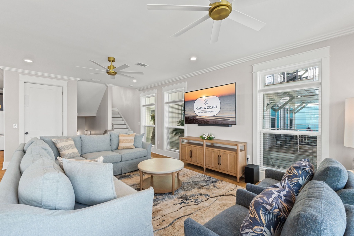 Sink into plush seating and let the gentle hum of the ceiling fans set the mood for your coastal escape. Large windows fill your living space with natural light while you unwind in this inviting retreat.