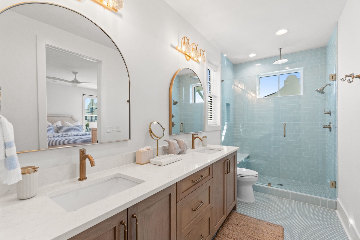 Your private spa-like bathroom features dual vanities, luxurious marble countertops, and a stunning walk-in shower with calming blue tiles.