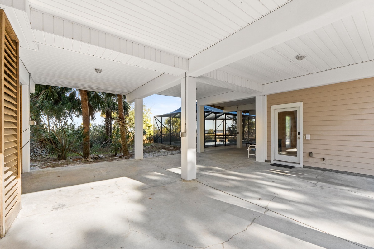 Covered parking area with tropical landscaping creates a welcoming arrival experience at this beachside property.