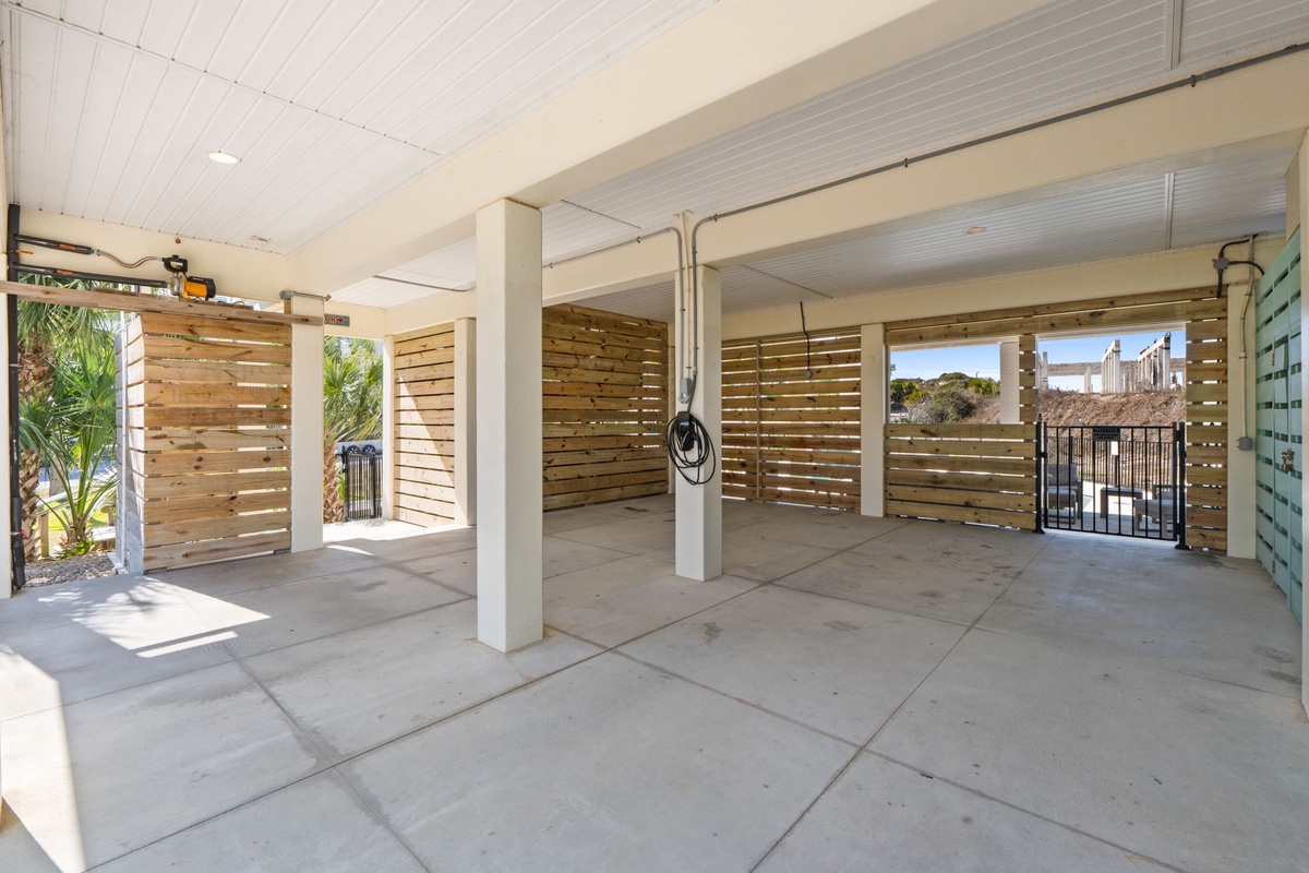 Spacious covered parking area with tropical palm trees and city views visible beyond the secure gates.