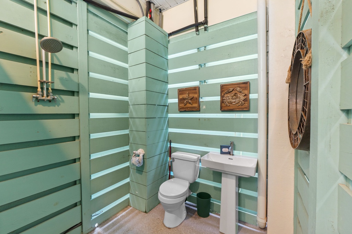 Freshen up in your unique bathroom featuring sea-green wooden slat walls and artistic touches that create a tropical, cabin-like atmosphere.