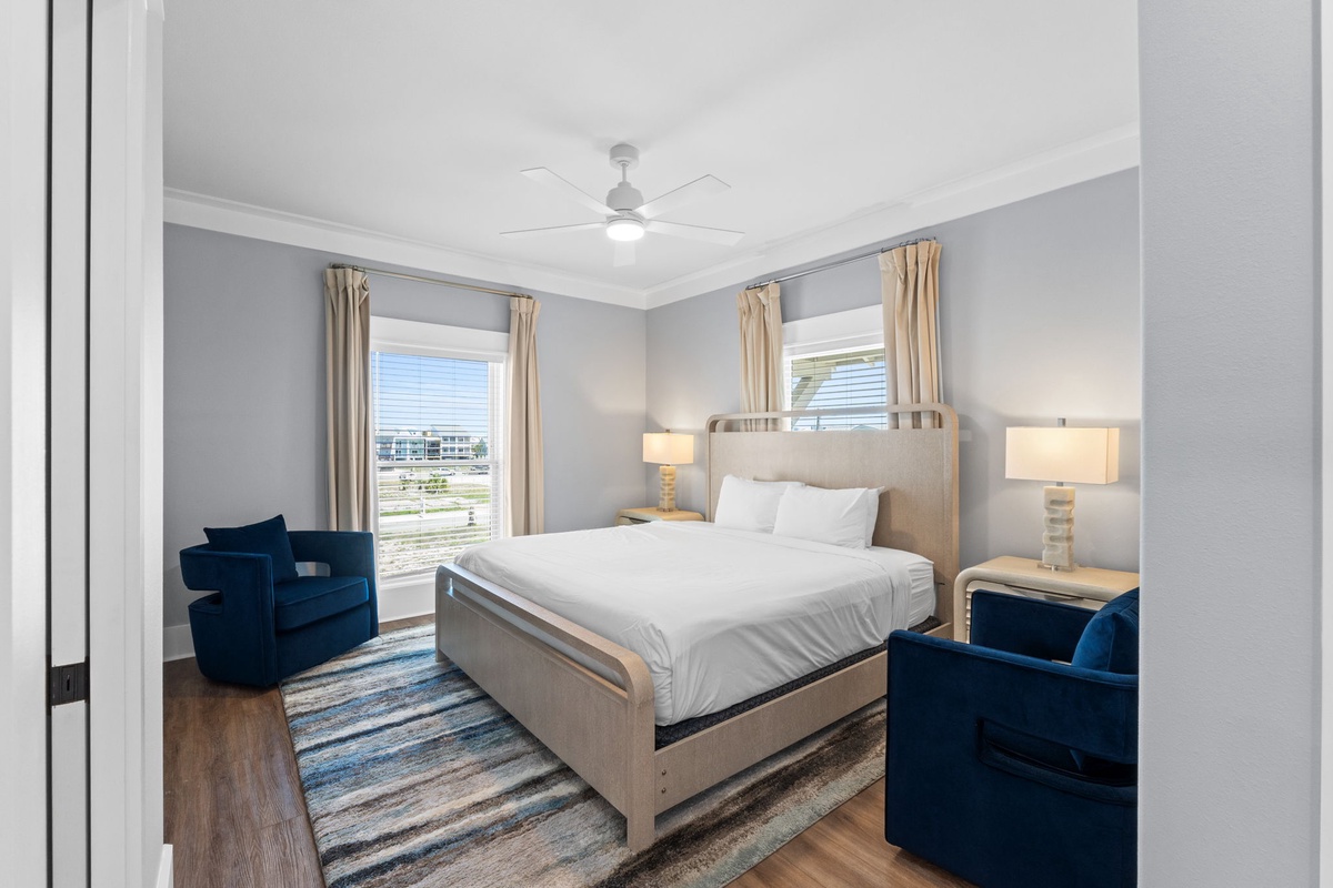 Your serene bedroom retreat awaits with a plush bed, elegant blue accent chairs, and soft natural light streaming through the windows—designed for your most restful nights.