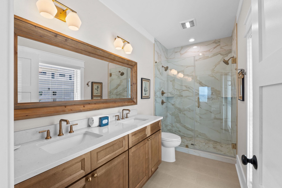 Refresh in your elegant bathroom featuring a spacious walk-in shower with luxurious marble-inspired tile and double vanity with warm wood accents—your personal sanctuary.