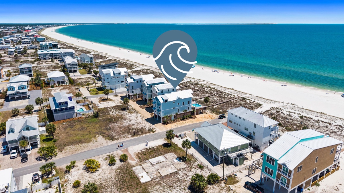 Aerial view of beachfront properties steps from pristine white sand and turquoise Gulf waters, featuring modern coastal homes in a relaxed neighborhood setting.