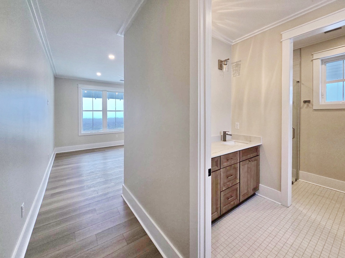 Your bright bathroom features elegant white vanity and opens to a sunlit room with stunning water views through large windows.
