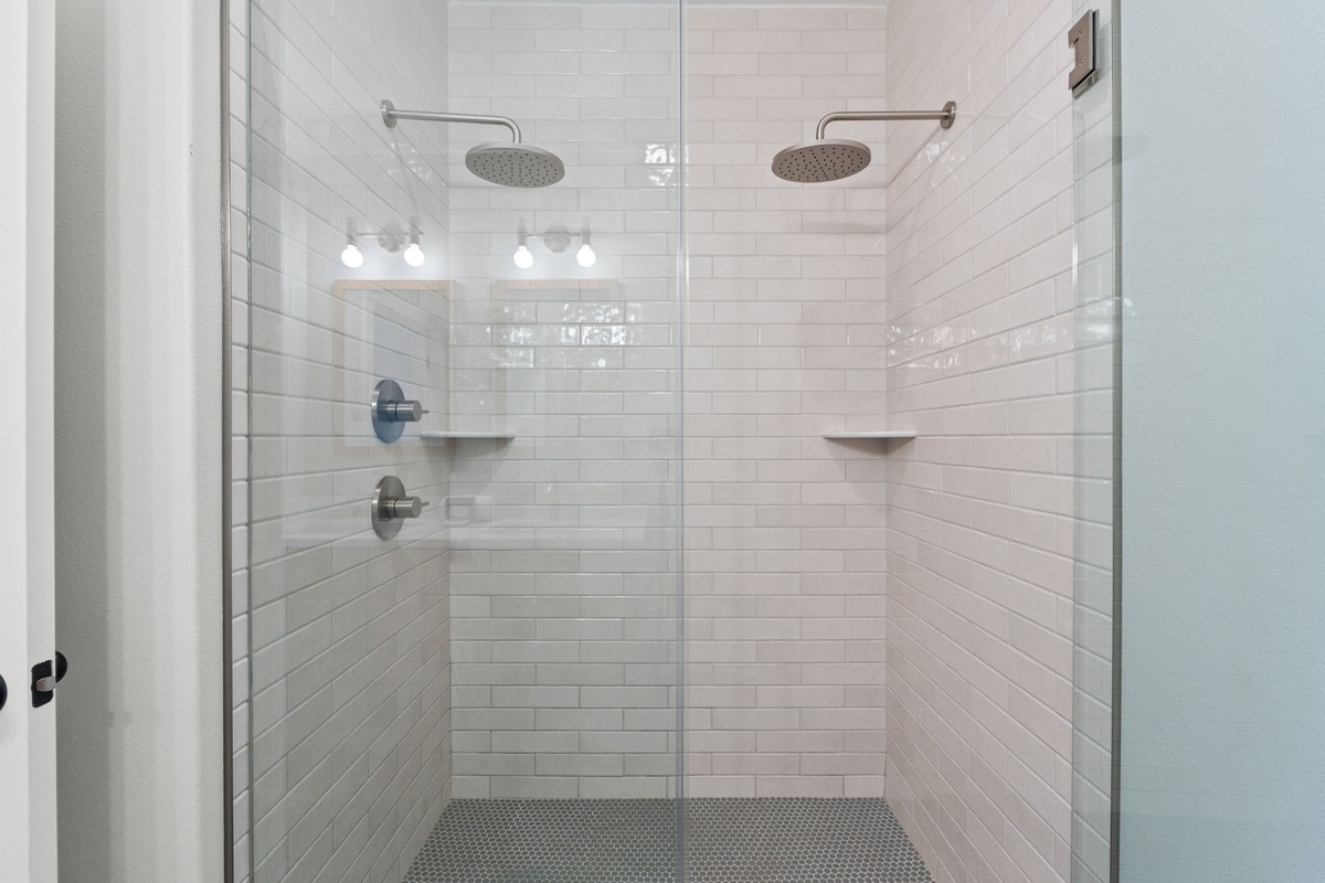 A pristine walk-in shower with dual rainfall heads and elegant white subway tile invites you to refresh after your day's adventures.
