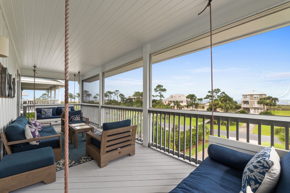 A screened porch overlooking coastal homes and green lawns provides a peaceful setting for morning coffee or evening relaxation.